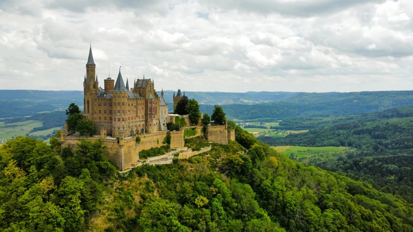 a castle sitting on top of a cliff in the middle of a lush green forest