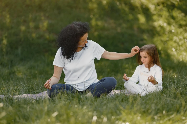 a mother and daughter sit in the grass while having fun