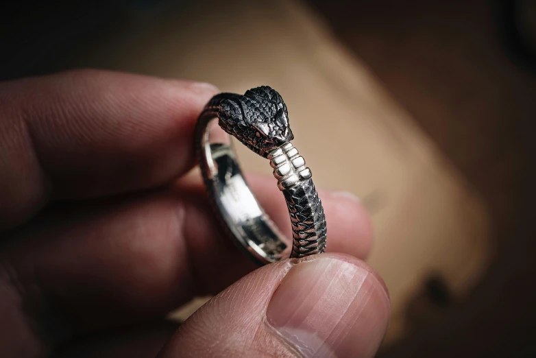 a man holds a small silver ring in his hands