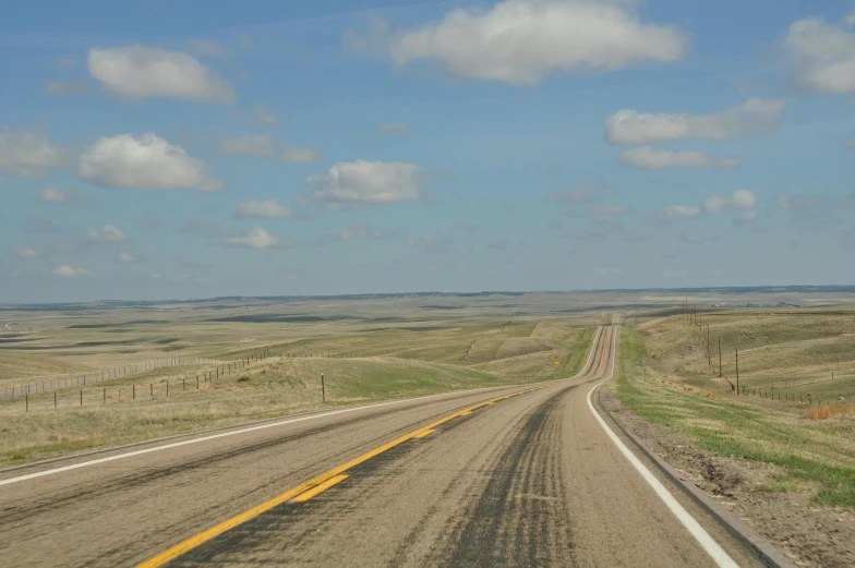 an empty road going through the middle of a plain