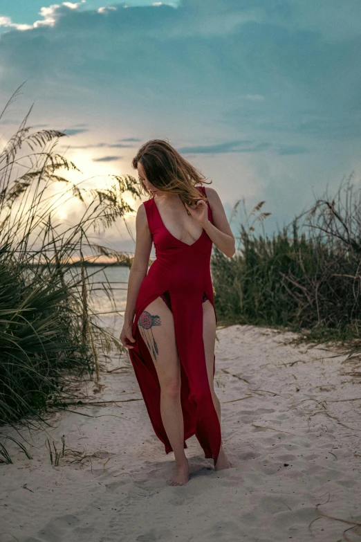 a woman wearing a red dress walking on the beach