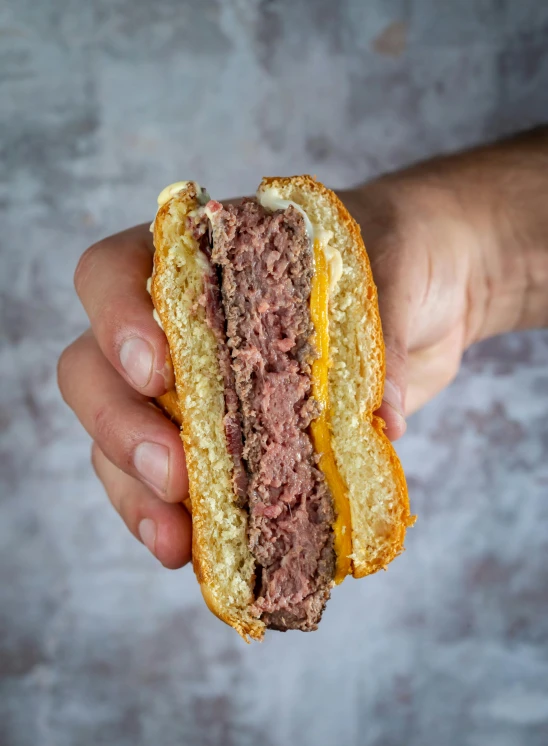 a person holds up a beef sandwich with mustard