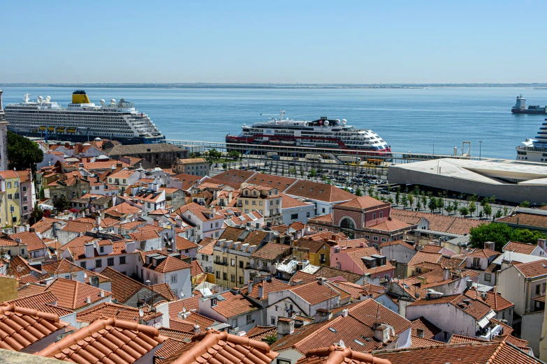 an aerial view of a large cruise ship in the background and buildings with roofs covered in tile