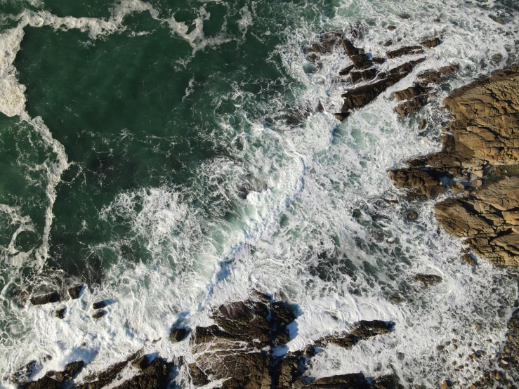 aerial view of a rocky coastline with foaming waves