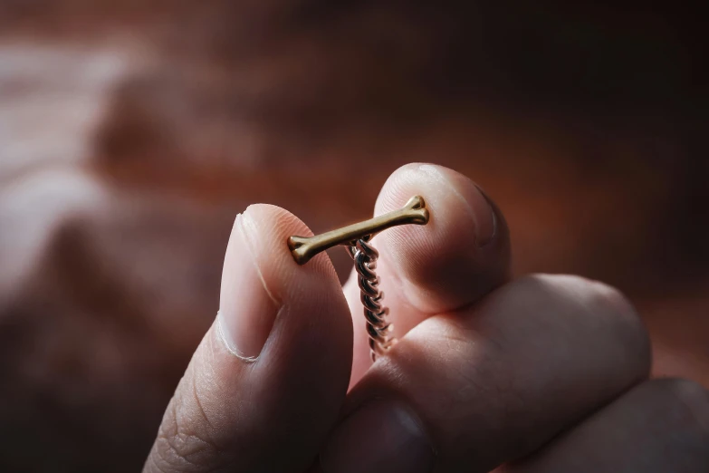 a hand holding a small gold tooth stick