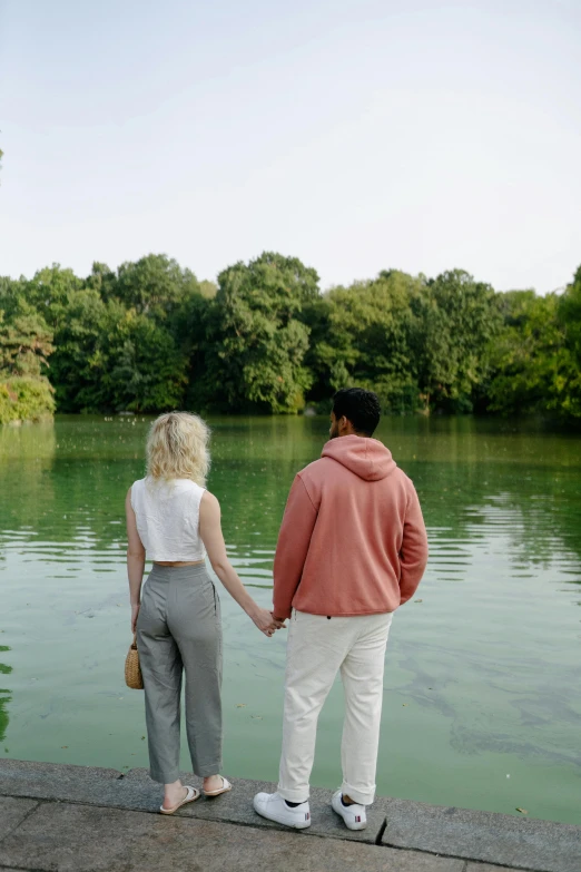 a man and woman holding hands near a lake