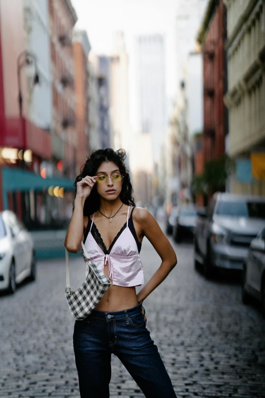 an attractive woman standing in the middle of a cobblestone street