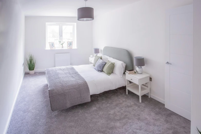 a bedroom with a white bed, white dresser and two lamps