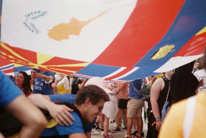 a man hugging another while standing under a large flag