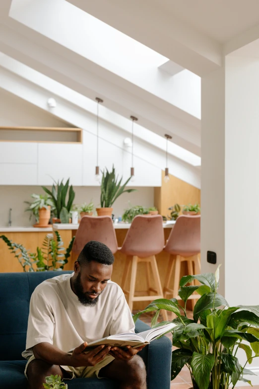 a man sitting on top of a couch reading a book