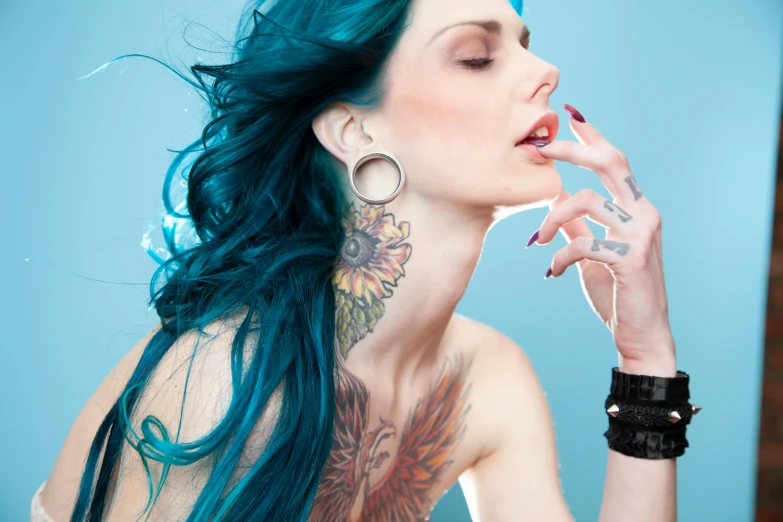 an attractive woman with green hair and tattoos posing for a po