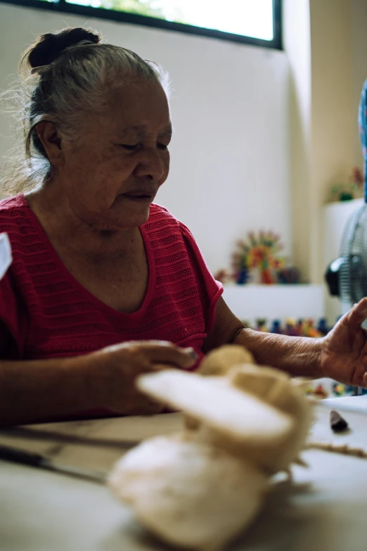 an elderly woman sitting at a counter in front of a plate of food