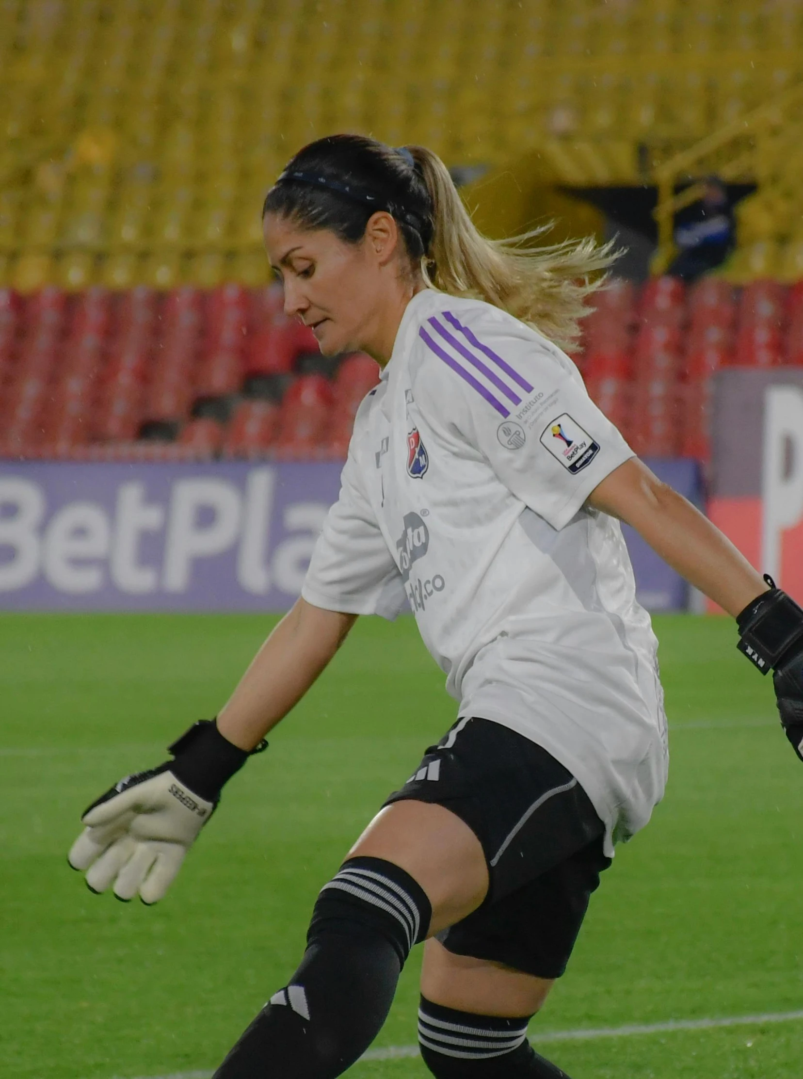 a women in a white shirt is kicking a soccer ball