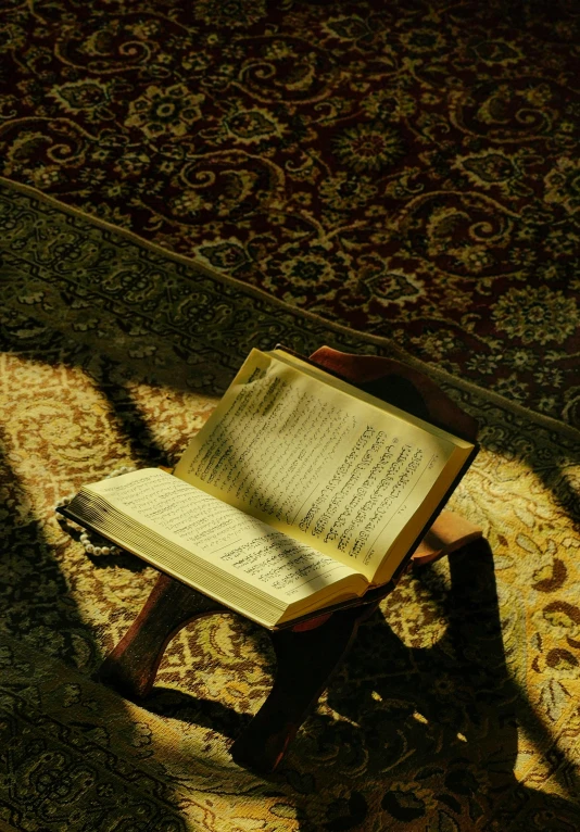 an open book on a small wooden chair on the floor