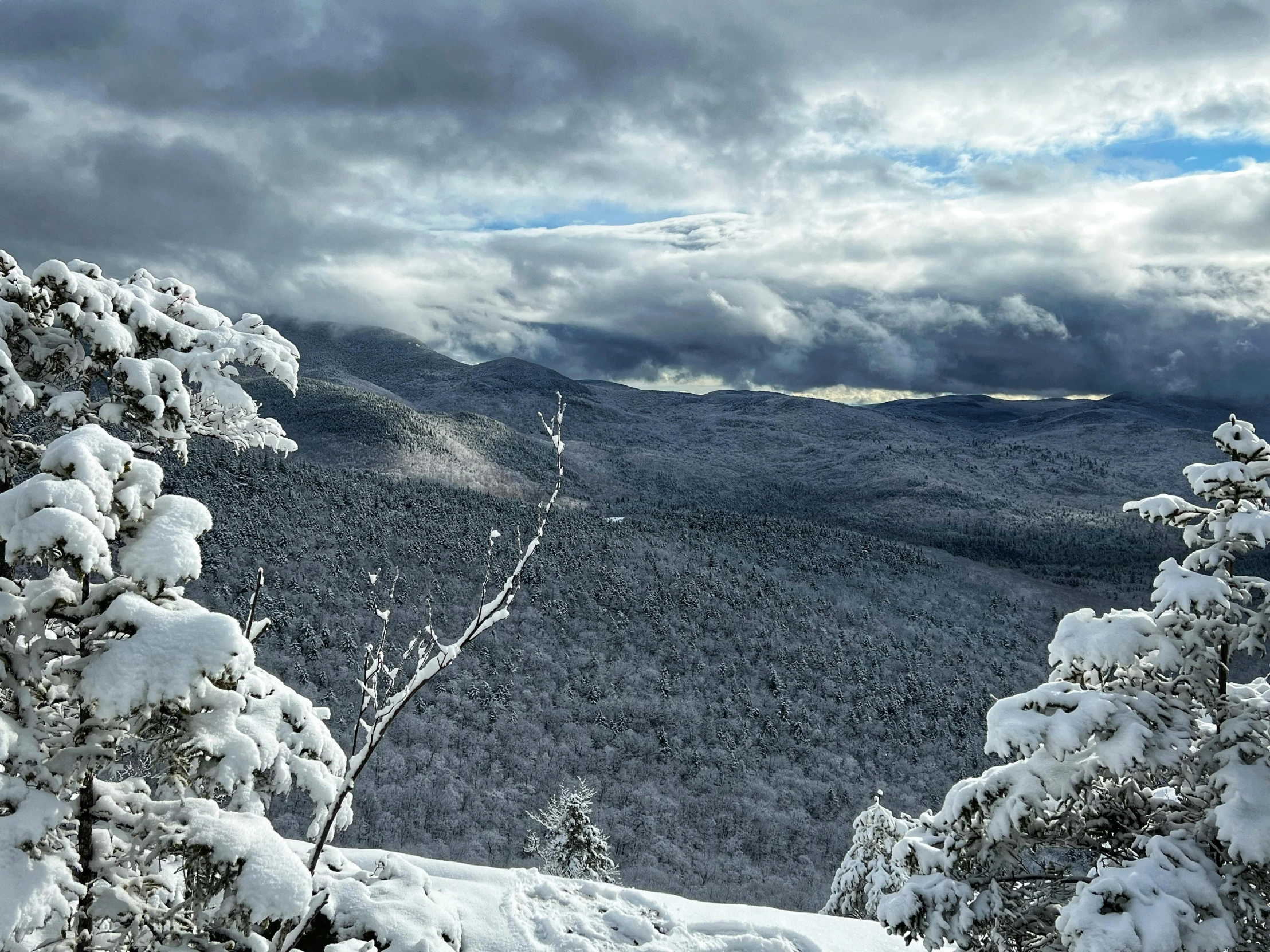 the mountains are covered with snow as clouds loom above