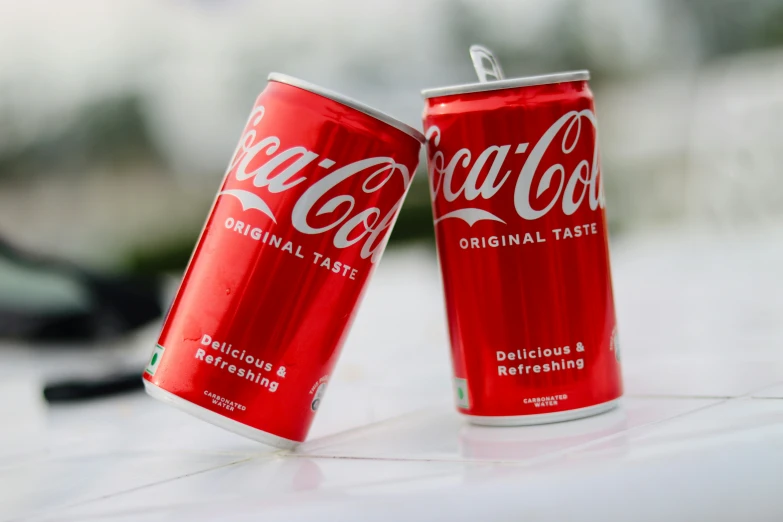 two cans of coca - cola sitting on a counter