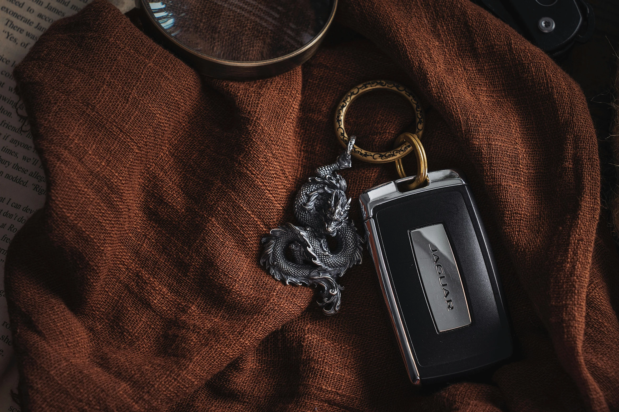 an open bottle with a key chain attached sits on top of an old book