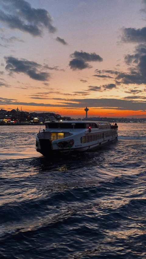 a ferry is going down the water during sunset