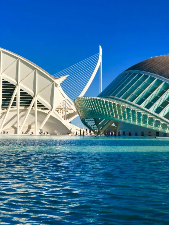 two modern buildings on top of water with people in the background