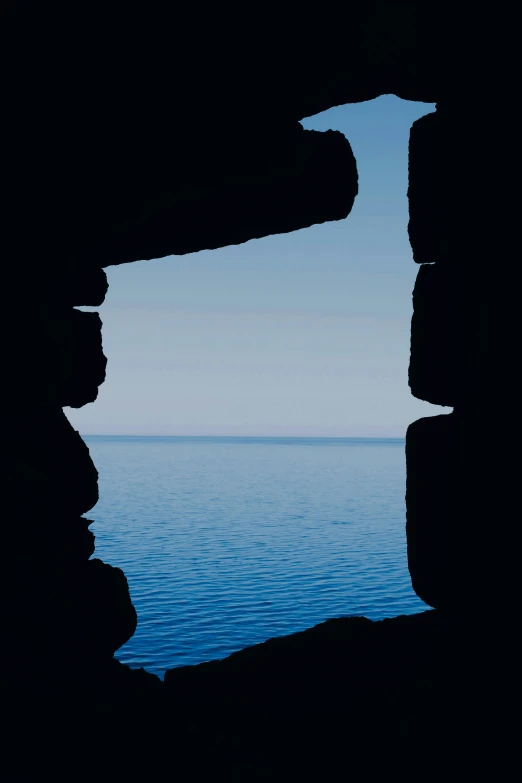 a beautiful view of the water and the sky through a small  in the rock