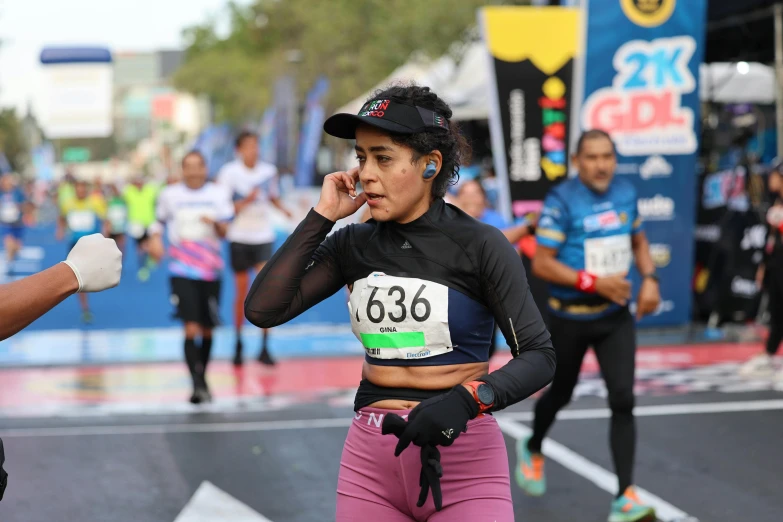 the runner wearing a black top is talking on her cell phone