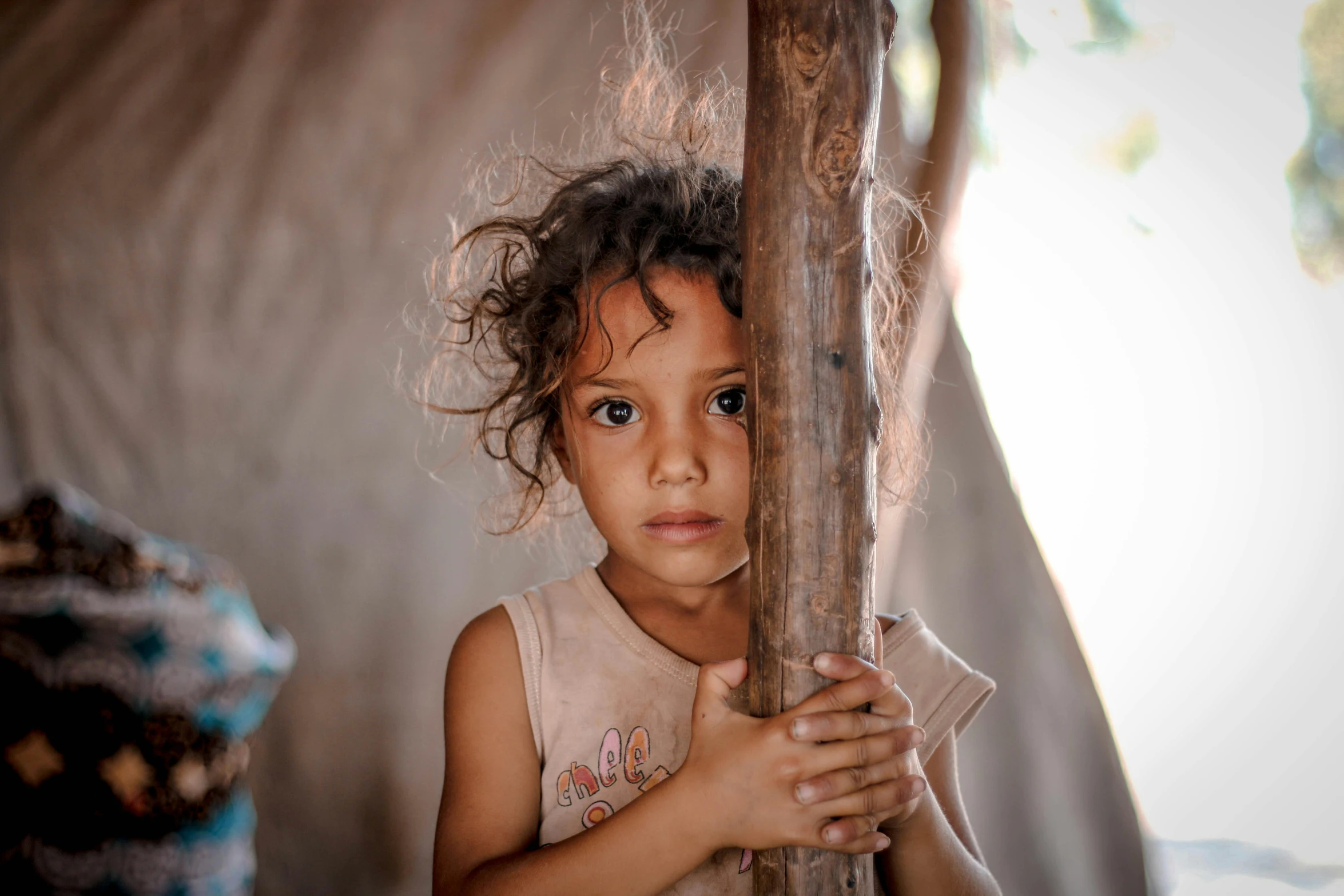 a little girl holding up a wooden stick