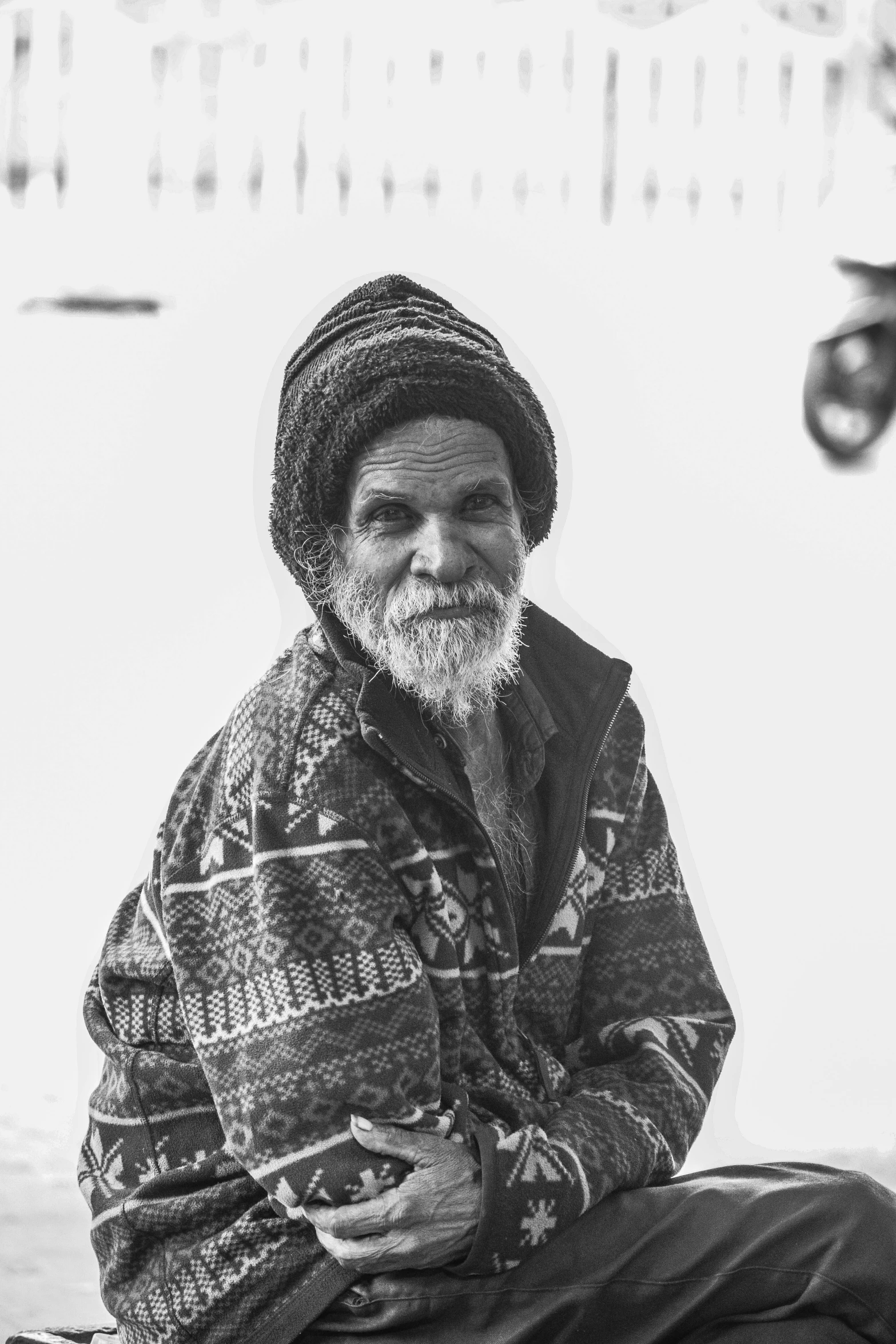 a man in a coat and hat sitting on the ground