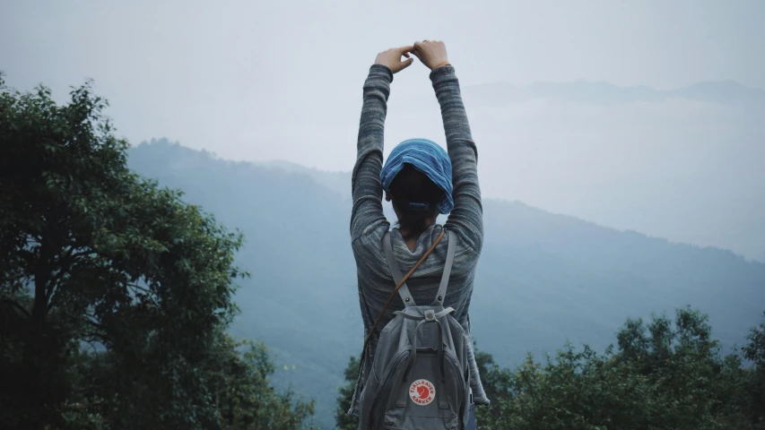 a young woman holding her hands up above her head