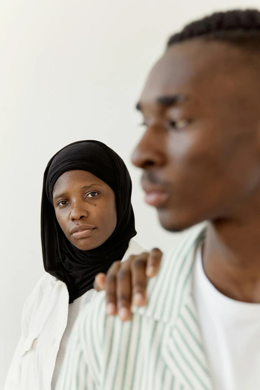 a man and a woman standing in front of white wall