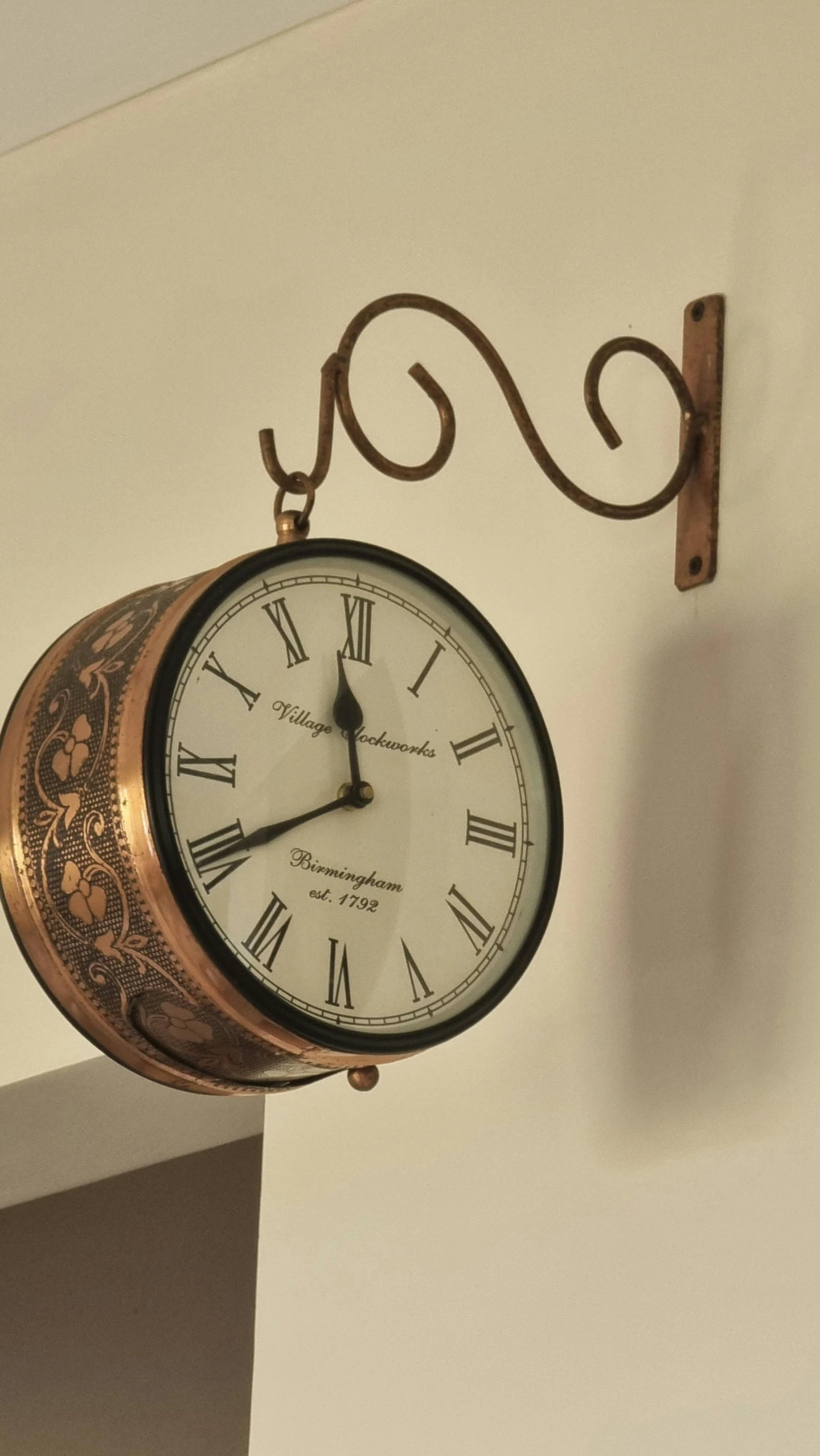 a large clock hanging from the wall behind an iron scaffolding