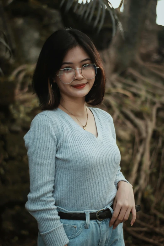 a woman is wearing glasses and is standing in front of a tree