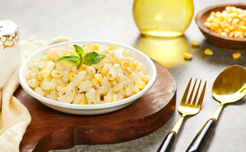 a bowl full of macaroni and cheese on a wood  board