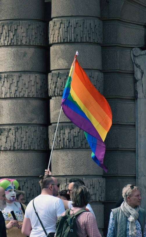 group of people gathered around looking at large rainbow flag