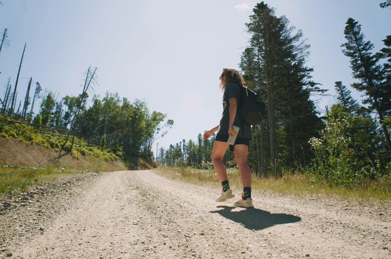 a female runner in shorts and white sneakers riding her bicycle on a dirt road