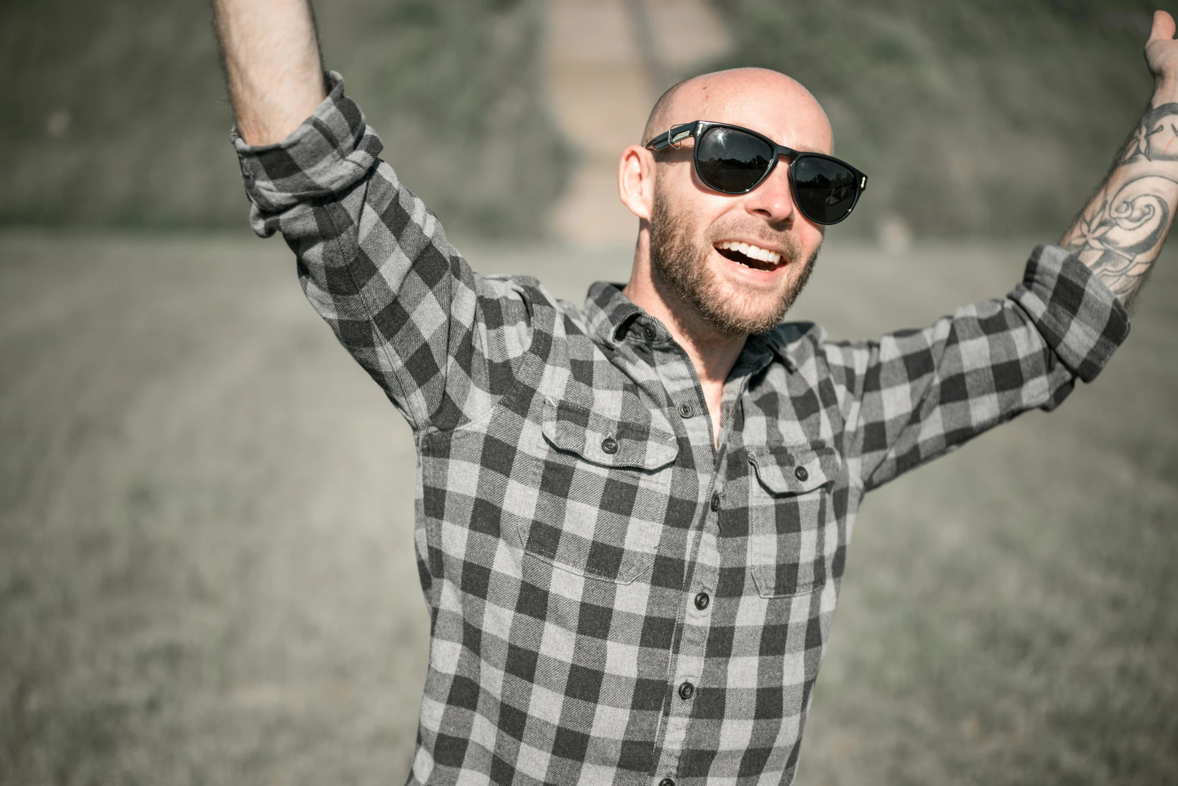 a bald man with shades raising his arms in the air