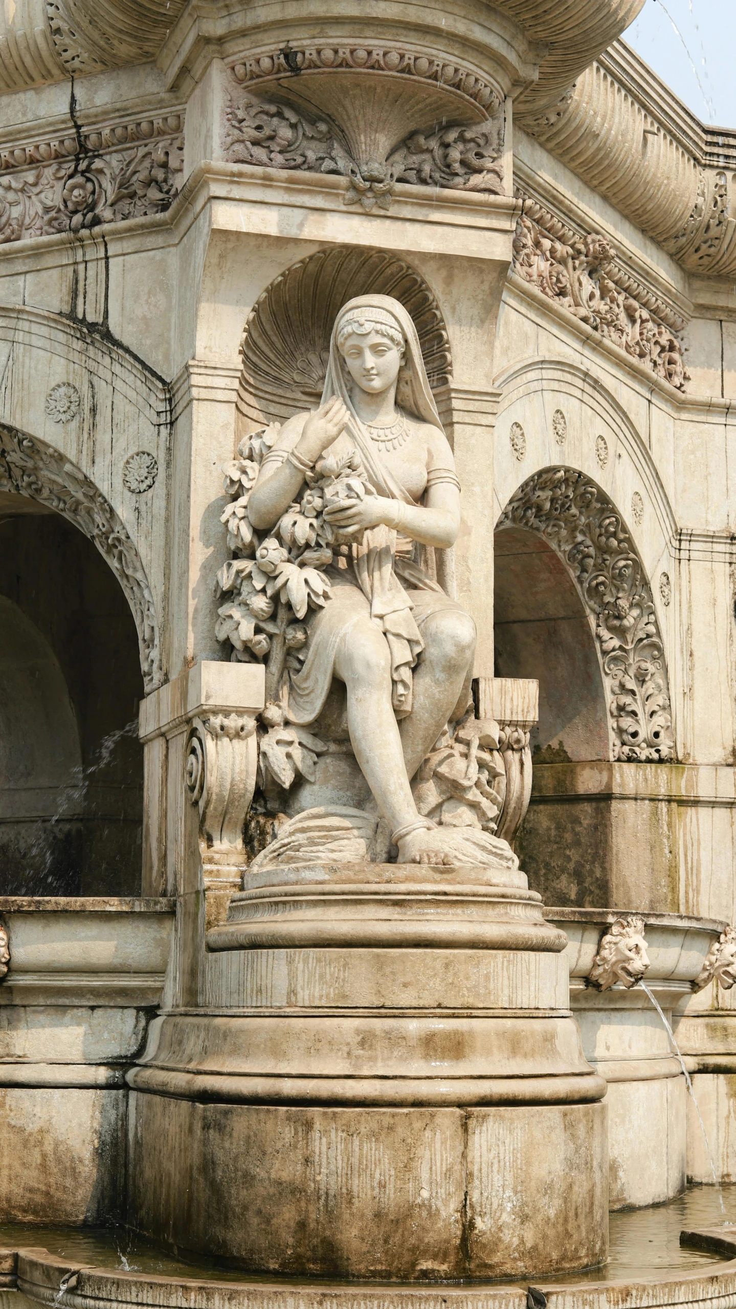 statue of lady with flowers and vase in front of ornate building