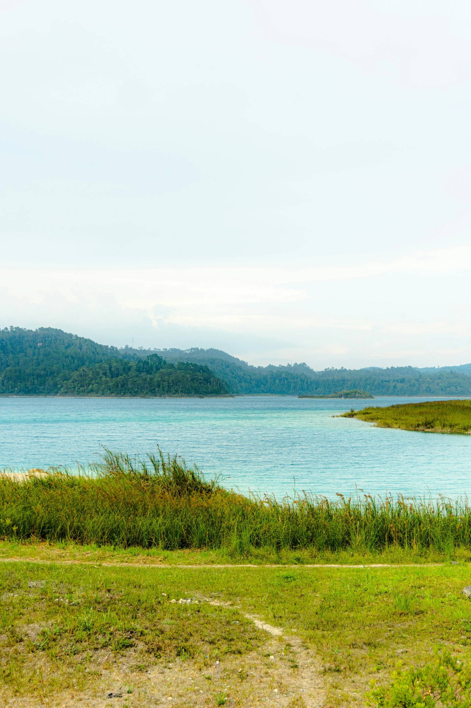 two people walking along the shoreline of a lake