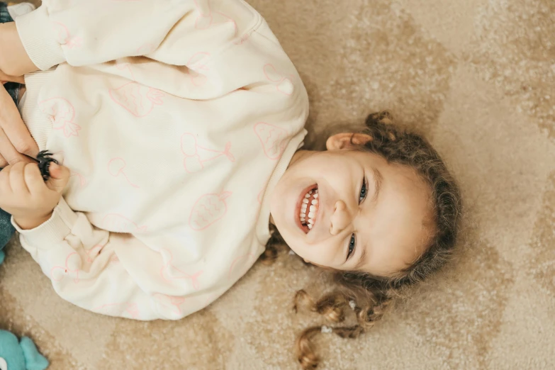 a small child smiles while laying on the floor