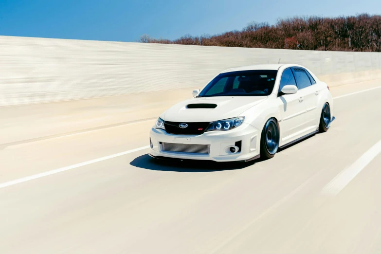 a white car driving down a long road