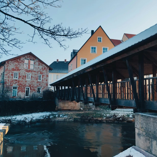 a small river flowing under a bridge covered in snow