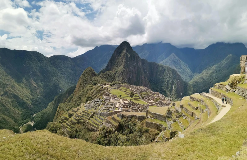 an ancient city stands atop a mountain with majestic hills