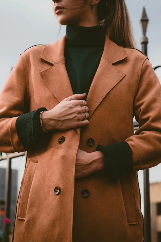 the woman is wearing an orange peacoat with black sweater