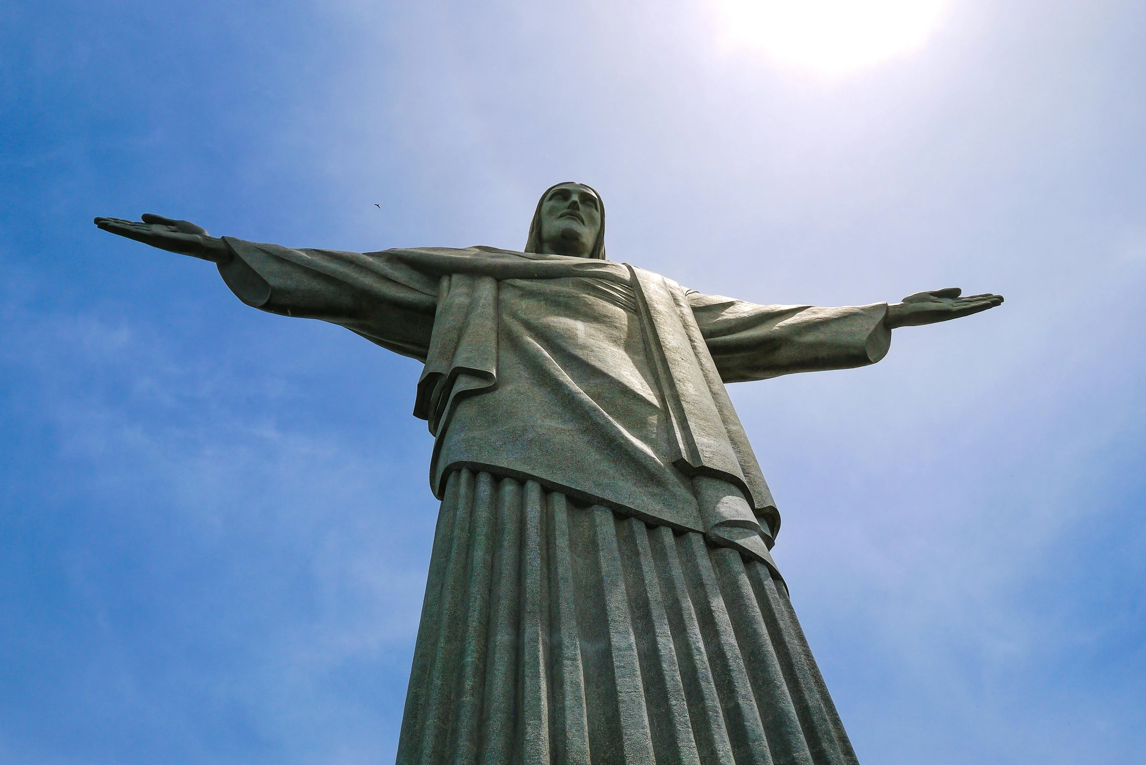 a statue of the jesus christ standing on top of a hill