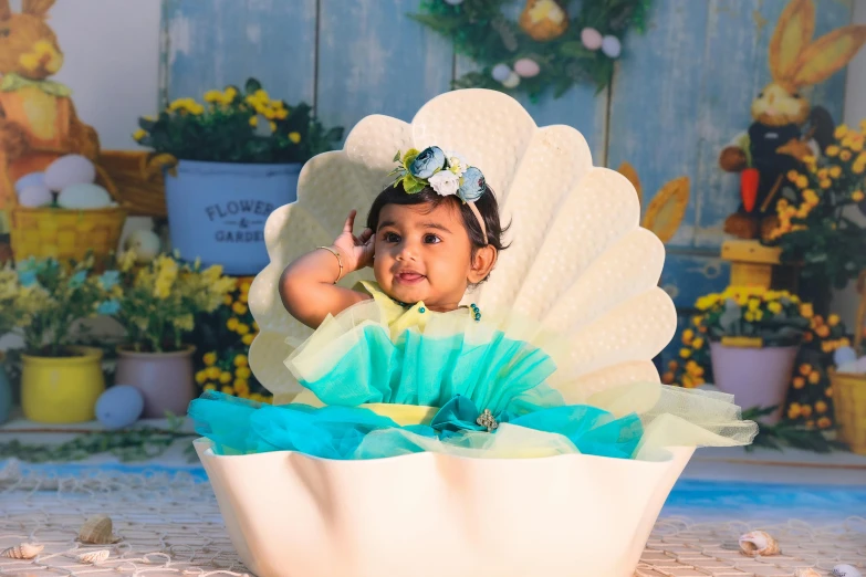 the little girl dressed in a blue and green outfit is sitting on a chair