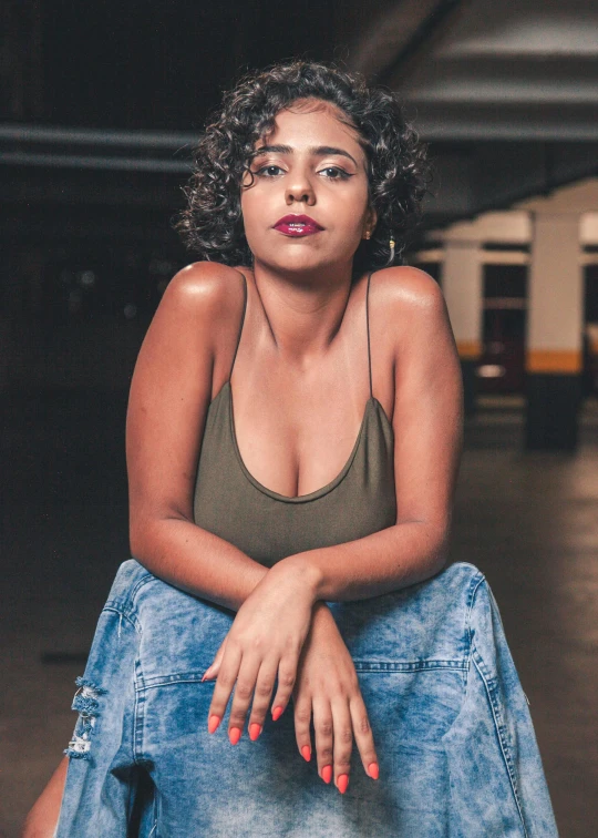 a black woman with bright red nails and a  sits on a concrete floor