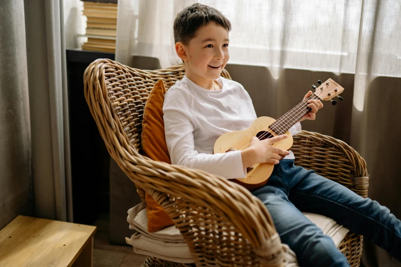 a boy holding a ukulele on a chair