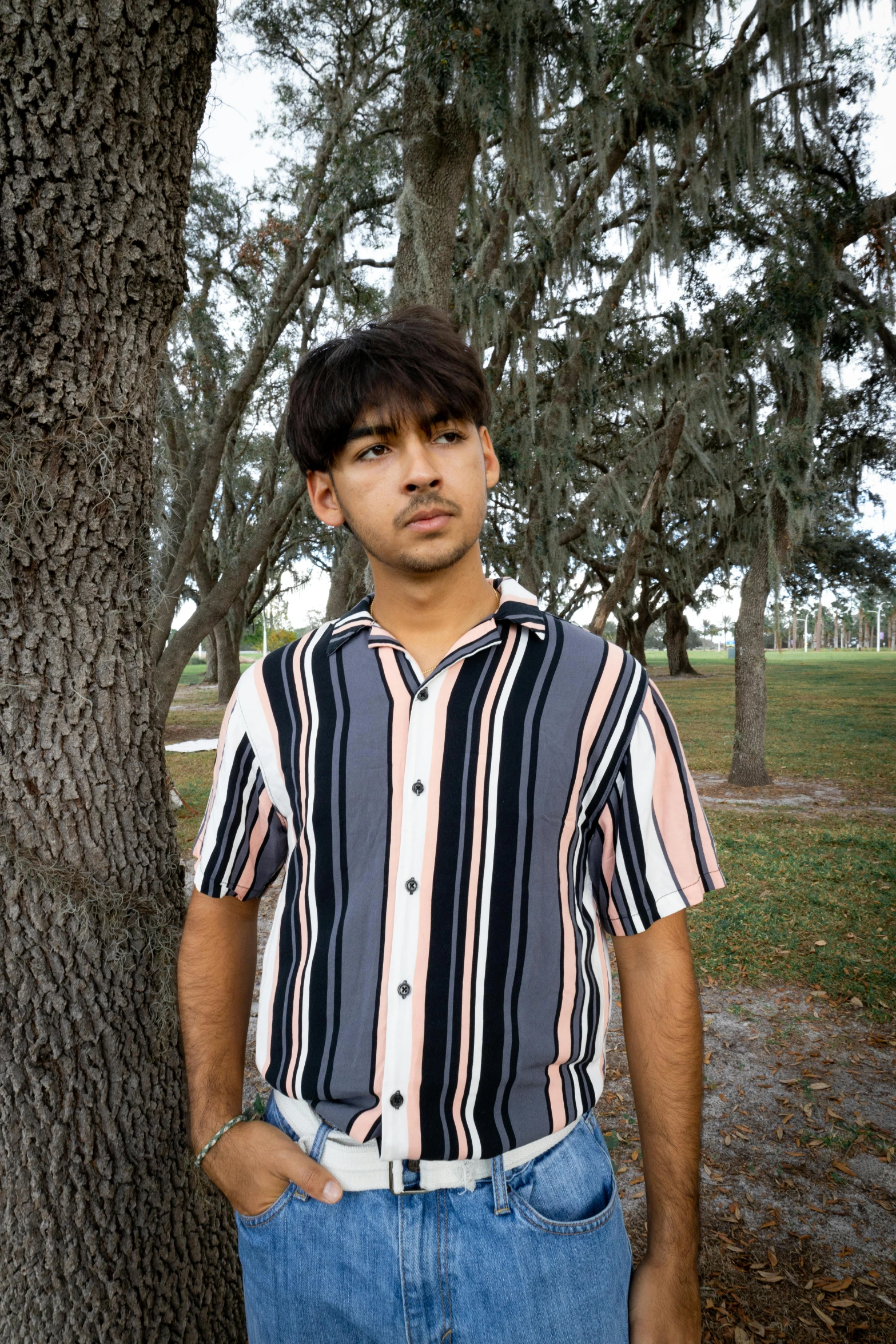 the man is wearing a shirt and jeans, looking at the camera