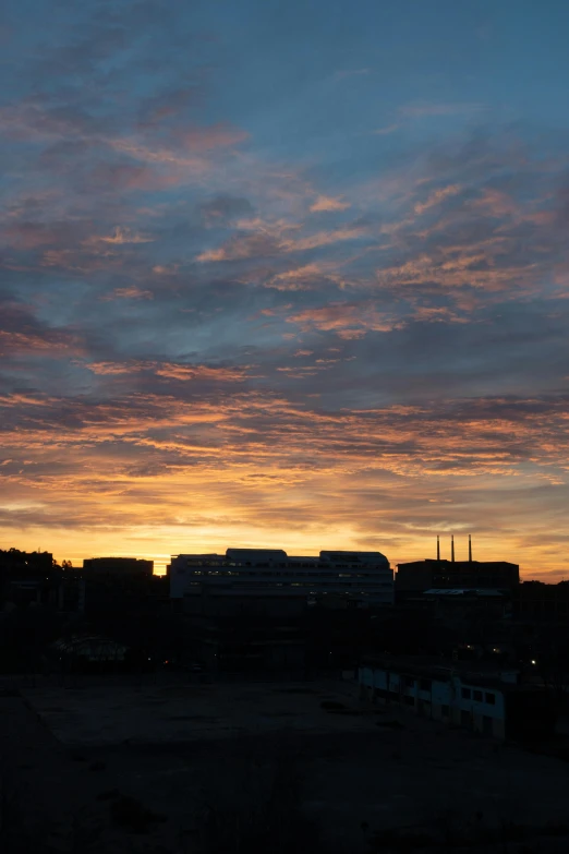 the sun is setting and some buildings are silhouetted