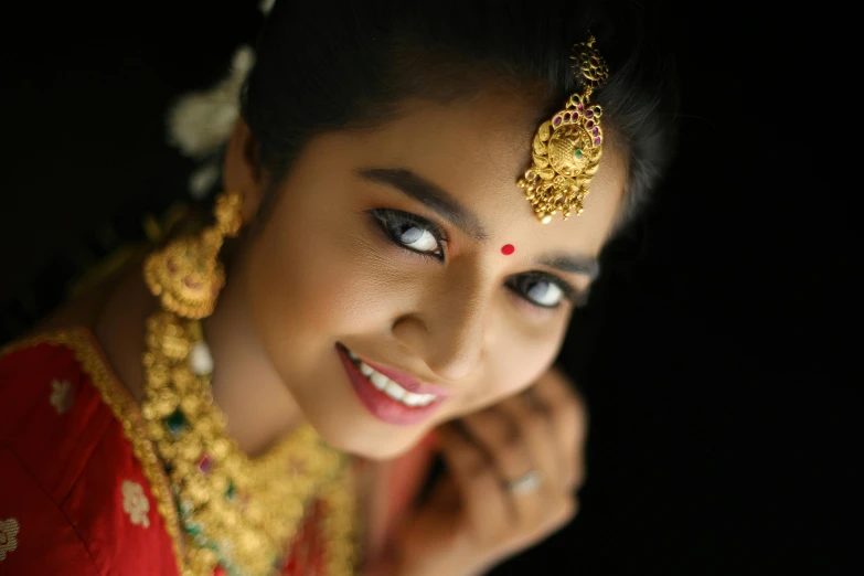 a woman in a red and gold attire wearing a golden necklace