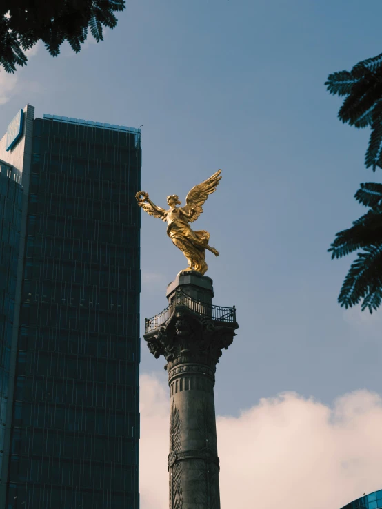 an angel statue is atop a tall pole